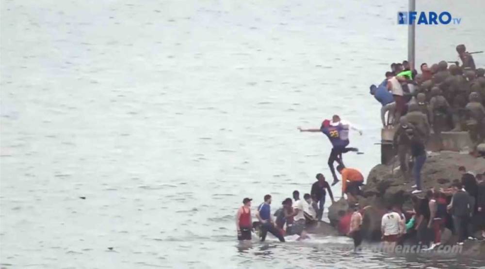 Des soldats espagnols usent de la force pour pousser des gens dans la mer